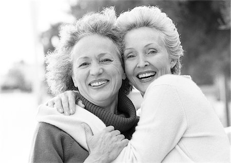 simsearch:400-06204561,k - Two mature women smiling at camera, one with arms around the other's shoulders, portrait, B&W Stock Photo - Premium Royalty-Free, Code: 695-05773447