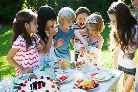 Girl opening gift at birthday party as friends watch Stock Photo - Premium Royalty-Free, Code: 695-05780004