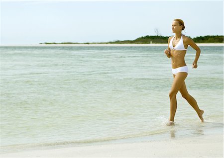 simsearch:400-03976636,k - Woman in bikini running in surf at beach Stock Photo - Premium Royalty-Free, Code: 695-03374125