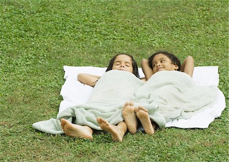 Two girls lying in grass, on a towel and covered with a towel Stock Photo - Premium Royalty-Free, Code: 695-03374354