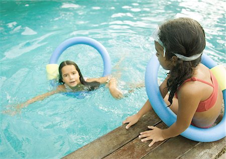 simsearch:695-03374346,k - Two girls with floating rings, one in pool, one sitting on edge of pool Stock Photo - Premium Royalty-Free, Code: 695-03374361