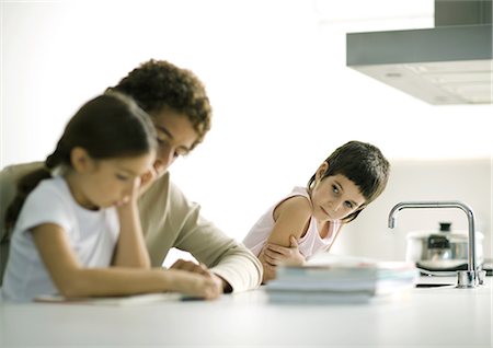Teenage boy helping younger sister with homework, second sibling watching Foto de stock - Sin royalties Premium, Código: 695-03374372