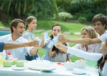 Family clinking cups over birthday cake Stock Photo - Premium Royalty-Free, Code: 695-03374453