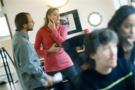 Man and woman speaking, woman looking at colleagues in foreground Stock Photo - Premium Royalty-Free, Code: 695-03374601