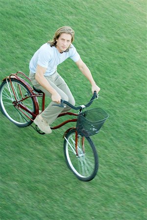 riding bike with basket - Young man riding bicycle across grass Stock Photo - Premium Royalty-Free, Code: 695-03375386
