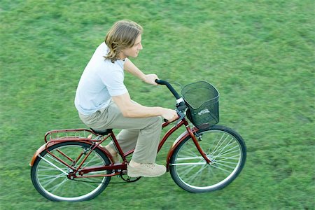 riding bike with basket - Young man riding bicycle across grass Stock Photo - Premium Royalty-Free, Code: 695-03375387