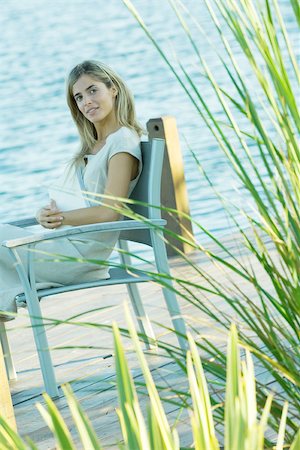 simsearch:633-01574151,k - Woman sitting on dock with book on lap, looking at camera Stock Photo - Premium Royalty-Free, Code: 695-03375397