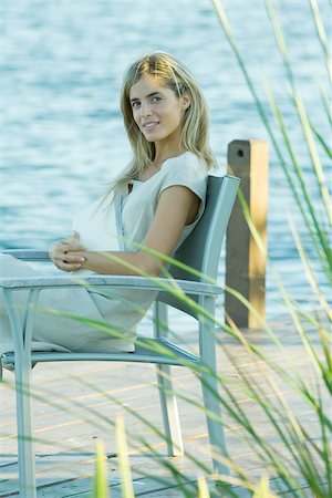 simsearch:633-01574151,k - Woman sitting on dock with book on lap, looking at camera Stock Photo - Premium Royalty-Free, Code: 695-03375398