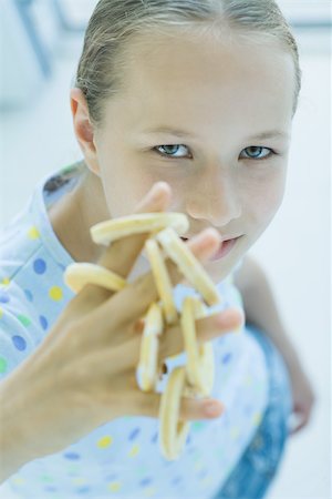 preteens fingering - Girl holding round cookies on fingers, looking at camera Stock Photo - Premium Royalty-Free, Code: 695-03375563