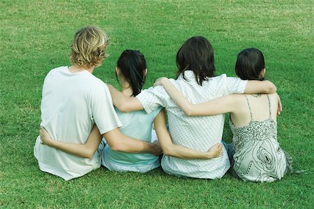 simsearch:633-01715612,k - Four young friends sitting on grass, side by side, with arms around each other, rear view Stock Photo - Premium Royalty-Free, Code: 695-03375719