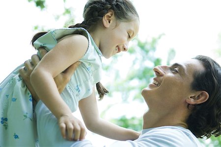 Girl and father, man lifting girl into the air Stock Photo - Premium Royalty-Free, Code: 695-03375830