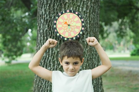 dartboard - Boy standing in front of dart board on tree, arms up Stock Photo - Premium Royalty-Free, Code: 695-03375831