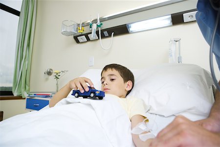 simsearch:632-01613036,k - Boy lying in hospital bed, holding toy Stock Photo - Premium Royalty-Free, Code: 695-03375859