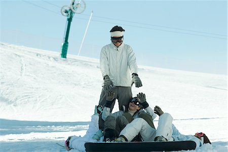 simsearch:696-03401677,k - Young snowboarders lying on ground reaching for young man standing behind them Stock Photo - Premium Royalty-Free, Code: 695-03376165
