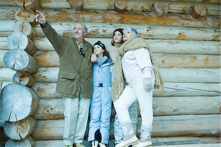 simsearch:696-03401677,k - Senior couple standing with teen and preteen granddaughters in front of log cabin, man pointing to the distance Stock Photo - Premium Royalty-Free, Code: 695-03376182