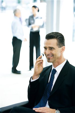 simsearch:695-03376228,k - Businessman sitting, using cell phone, smiling Stock Photo - Premium Royalty-Free, Code: 695-03376228