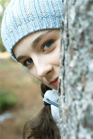 Teenage girl peeking around tree trunk, looking at camera, portrait Foto de stock - Sin royalties Premium, Código: 695-03376427