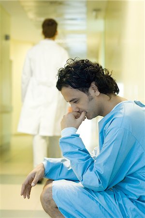 simsearch:632-01613036,k - Male patient crouching in hospital corridor, holding head, looking down, doctor walking away in background Stock Photo - Premium Royalty-Free, Code: 695-03376435