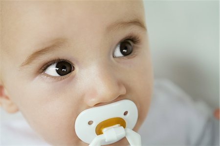 Baby with pacifier in mouth, raising eyebrows, close-up Stock Photo - Premium Royalty-Free, Code: 695-03376623