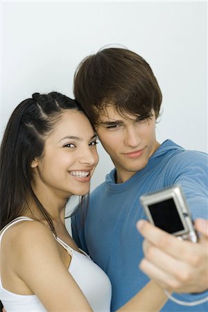 Young couple taking self portrait with digital camera, woman smiling at camera Stock Photo - Premium Royalty-Free, Code: 695-03376690