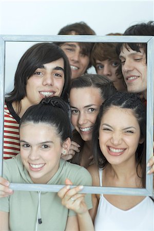 simsearch:695-03376693,k - Groupe de jeunes amis qui posent pour la photo, brandissant cadre photo, souriant à la caméra, portrait Photographie de stock - Premium Libres de Droits, Code: 695-03376825