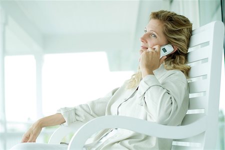 simsearch:695-03376228,k - Woman sitting on porch using cell phone, smiling, looking away Stock Photo - Premium Royalty-Free, Code: 695-03376940
