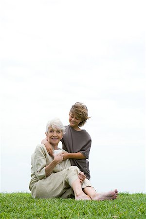 Senior woman sitting on grass, grandson handing her gift, full length Stock Photo - Premium Royalty-Free, Code: 695-03376977