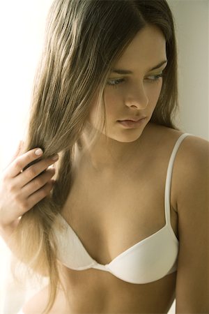 strand - Young woman in bra holding hair in hand, looking away Stock Photo - Premium Royalty-Free, Code: 695-03377096