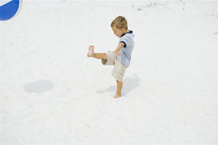 Young boy kicking beach ball at the beach, side view Stock Photo - Premium Royalty-Free, Code: 695-03377207
