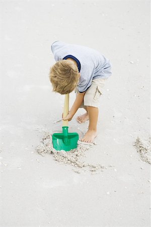 Young boy digging in sand with shovel, full length Stock Photo - Premium Royalty-Free, Code: 695-03377214