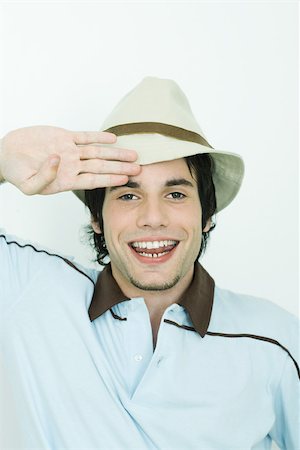 saluting - Young man wearing hat, saluting, smiling at camera Stock Photo - Premium Royalty-Free, Code: 695-03377385