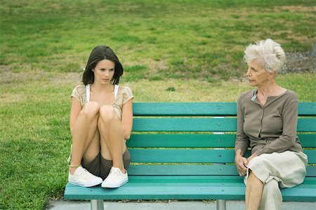 Teenage girl sitting apart from grandmother on bench, both frowning Stock Photo - Premium Royalty-Free, Code: 695-03377503