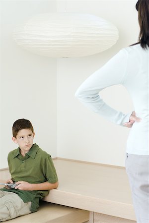 simsearch:632-03424261,k - Boy holding  video game glaring at mother who watches him with hands on hips Stock Photo - Premium Royalty-Free, Code: 695-03377537