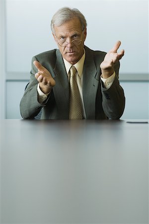 Businessman seated, gesturing with hands, looking at camera Stock Photo - Premium Royalty-Free, Code: 695-03377827