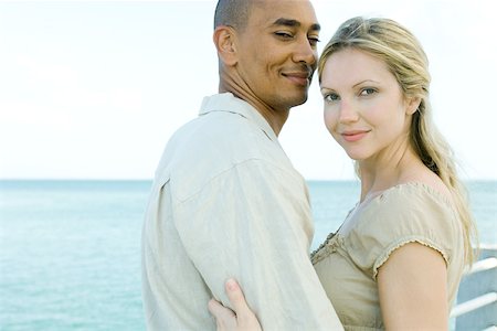 Couple embracing, both smiling at camera, ocean in background Stock Photo - Premium Royalty-Free, Code: 695-03377877