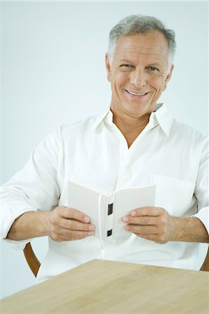 simsearch:632-03083700,k - Mature man sitting, holding book, smiling at camera Stock Photo - Premium Royalty-Free, Code: 695-03377896