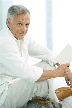 simsearch:632-03083700,k - Mature man sitting indian style, holding book, smiling at camera Stock Photo - Premium Royalty-Free, Code: 695-03377897