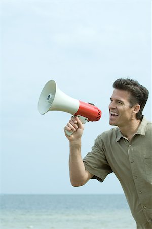 Man standing by the sea, shouting into megaphone, close-up Stock Photo - Premium Royalty-Free, Code: 695-03377921