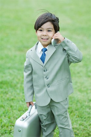 simsearch:695-05768235,k - Young boy dressed in suit, holding up cell phone, carrying briefcase Stock Photo - Premium Royalty-Free, Code: 695-03377931