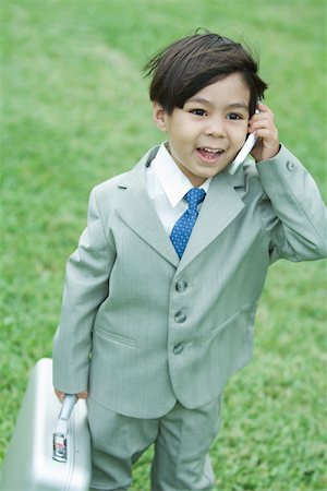 simsearch:695-05768235,k - Young boy dressed in suit, using cell phone, carrying briefcase Stock Photo - Premium Royalty-Free, Code: 695-03377932