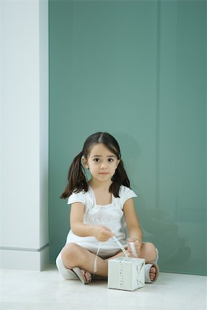 simsearch:632-01193783,k - Little girl sitting on the ground, tying ribbon on gift, looking at camera Stock Photo - Premium Royalty-Free, Code: 695-03377980