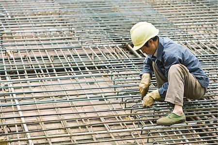 plugging in - Man crouching at construction site, building steel framework Stock Photo - Premium Royalty-Free, Code: 695-03378139