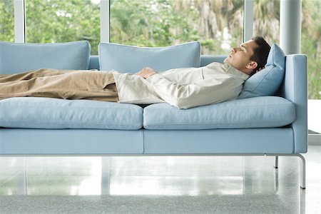 Man lying on couch with hand behind head, eyes closed, side view Stock Photo - Premium Royalty-Free, Code: 695-03378269