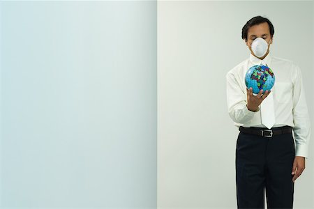 suffocated - Man wearing pollution mask, holding globe, eyes closed Stock Photo - Premium Royalty-Free, Code: 695-03378327