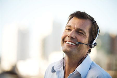 simsearch:695-03376228,k - Businessman using headset, smiling, close-up Stock Photo - Premium Royalty-Free, Code: 695-03378517