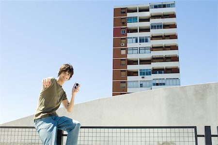 simsearch:614-07146649,k - Teenage boy sitting outdoors, listening to mp3 player, pointing at camera Foto de stock - Sin royalties Premium, Código: 695-03378590