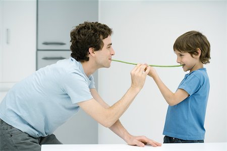 simsearch:695-03378605,k - Father and son standing face to face, holding up green beans between their mouths, side view Stock Photo - Premium Royalty-Free, Code: 695-03378604