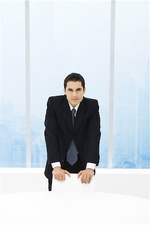simsearch:632-03403433,k - Businessman standing with hands on chair, looking at camera Stock Photo - Premium Royalty-Free, Code: 695-03378683