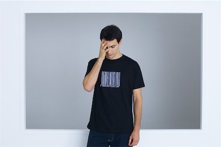 Man wearing tee-shirt printed with bar code, covering face with hand Stock Photo - Premium Royalty-Free, Code: 695-03378803