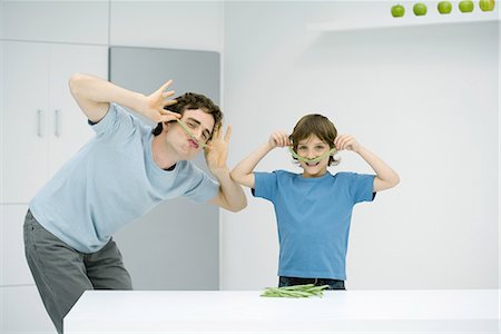 Man and boy in kitchen playing with food, smiling at camera Stock Photo - Premium Royalty-Free, Code: 695-03378903